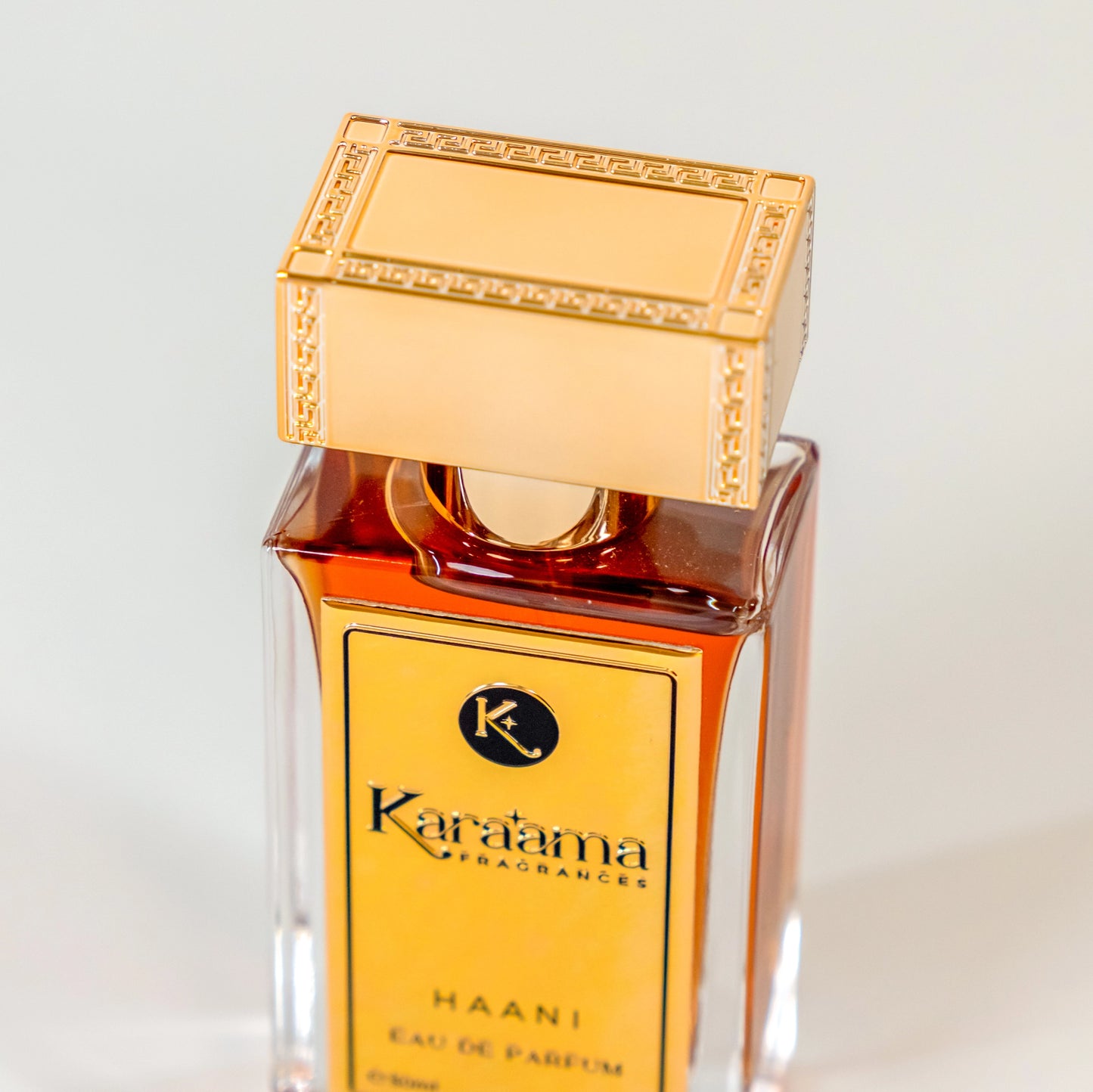 Elegant Káraama Haani Eau de Parfum bottle with rich amber liquid and gold accents, embodying luxury and sophistication in fragrance design. #Perfume #LuxuryFragrance #EauDeParfum #ScentTrend