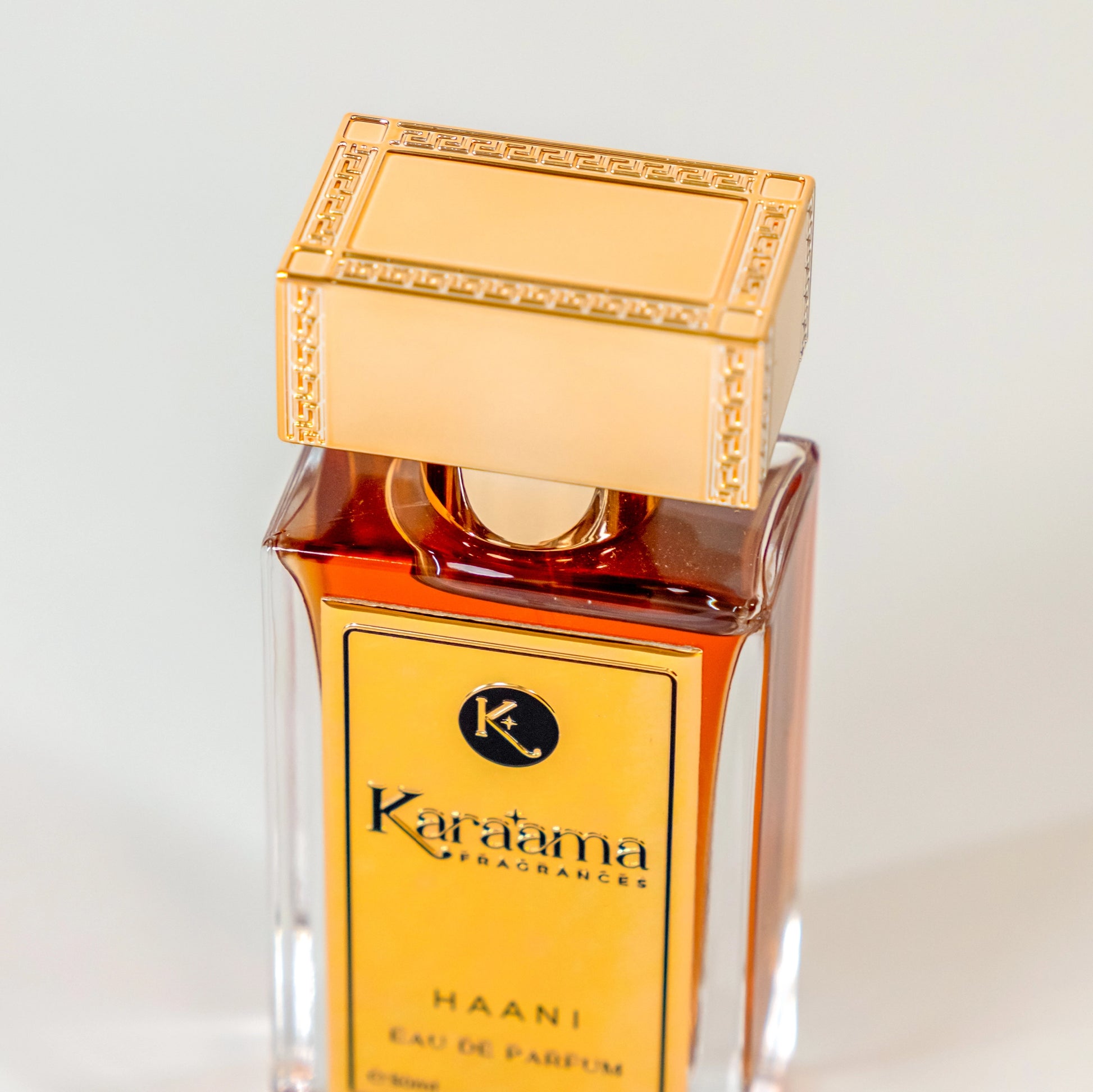 Elegant Káraama Haani Eau de Parfum bottle with rich amber liquid and gold accents, embodying luxury and sophistication in fragrance design. #Perfume #LuxuryFragrance #EauDeParfum #ScentTrend