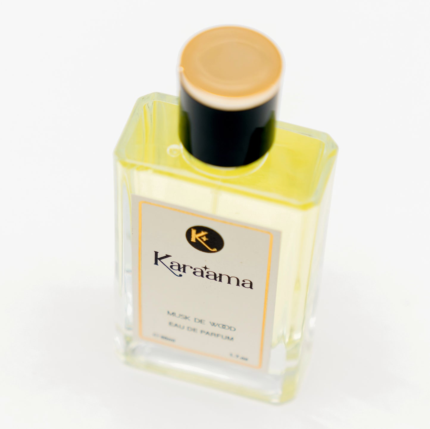 A bottle of Karaama Musk de Wood Eau de Parfum with a gold lid on a white table. The bottle is 50ml or 1.69 fl oz. [karaama.com]