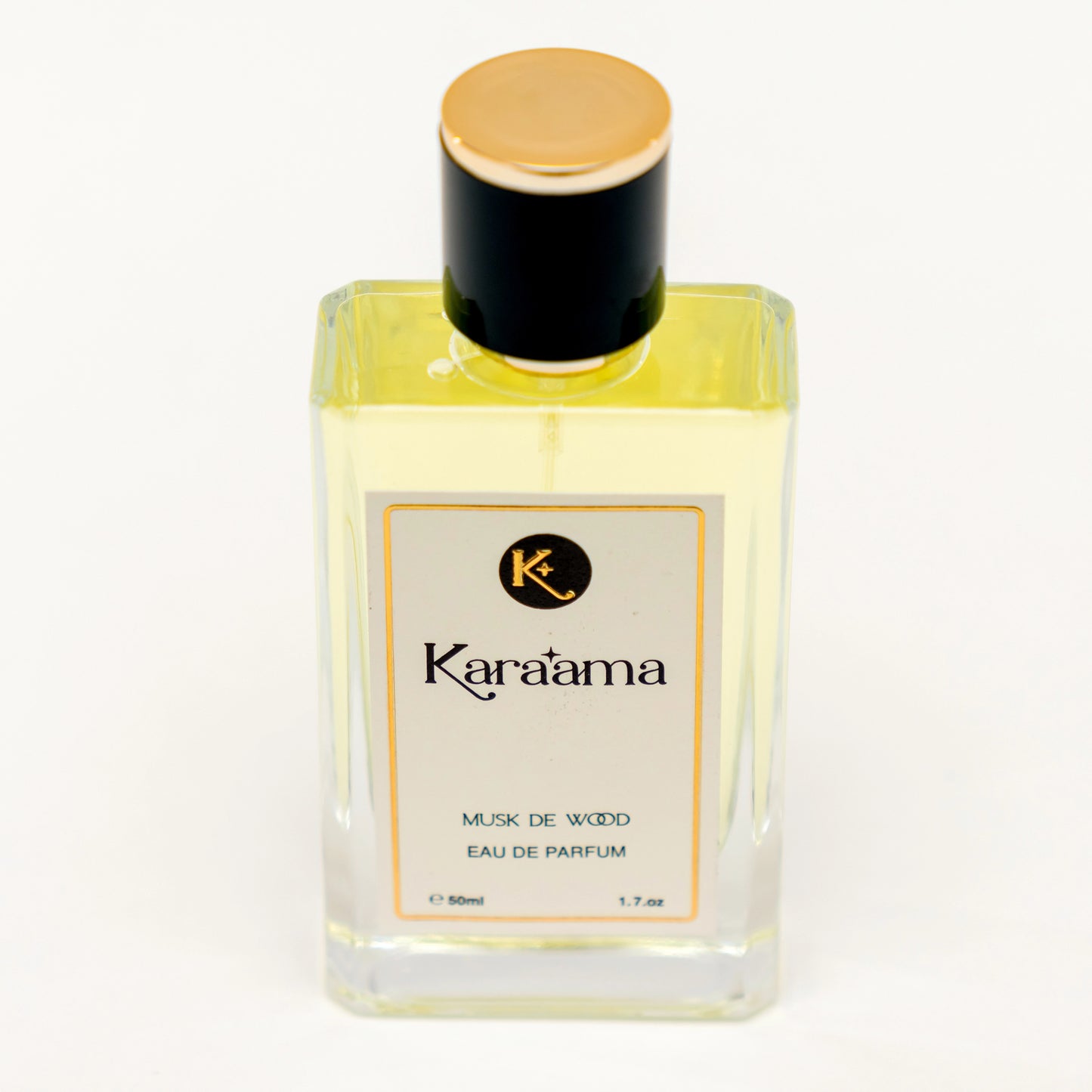 A bottle of Karaama Musk de Wood Eau de Parfum with a gold lid on a white table. The bottle is 50ml or 1.69 fl oz. [karaama.com]