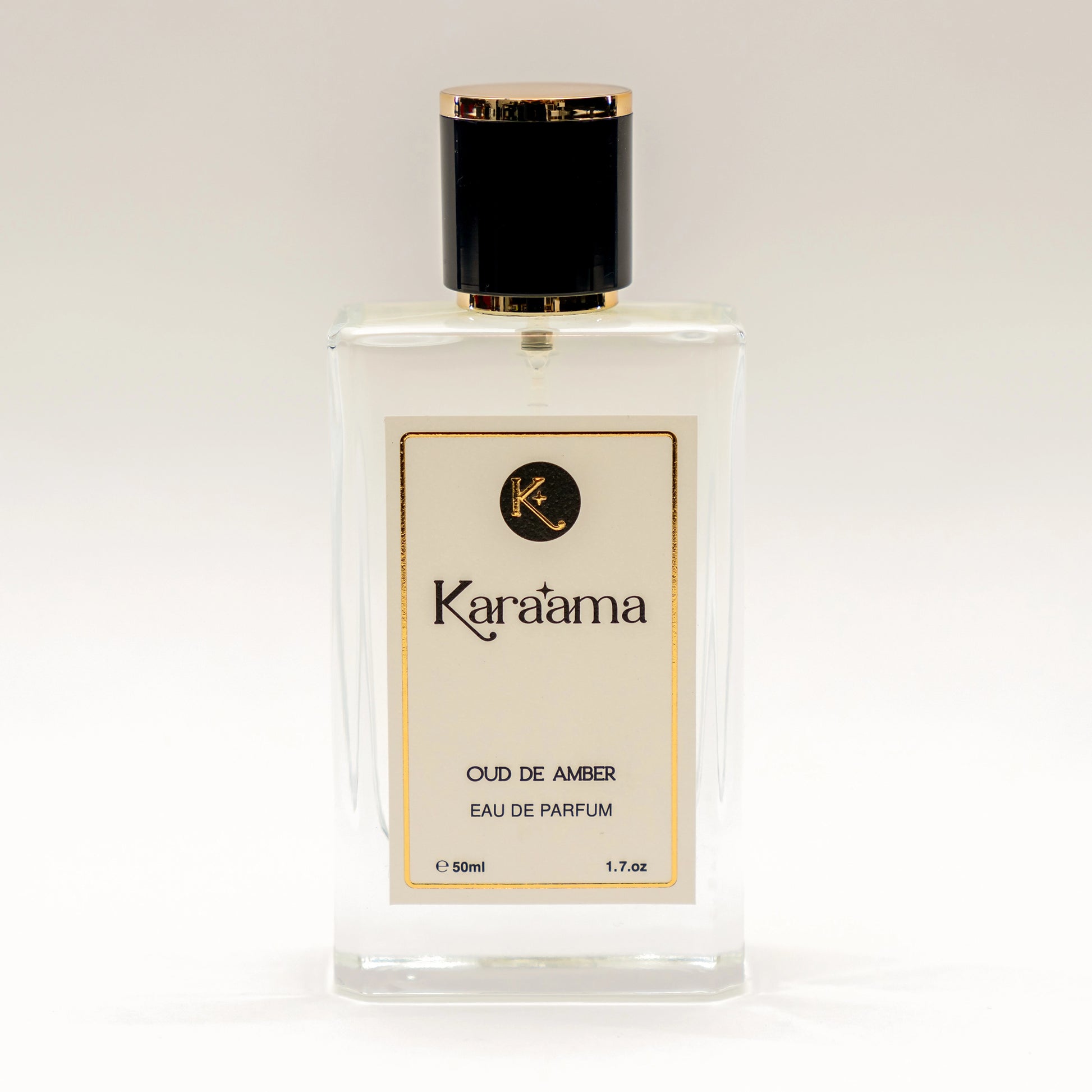 A bottle of Karaama Oud de Amber Eau de Parfum with a gold lid on a white table. The bottle is 50ml or 1.69 fl oz. [karaama.com]